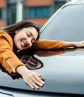 Happy woman hugging her car, showing affection and excitement.