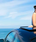 A woman sitting on top of her car, enjoying the view of the sea