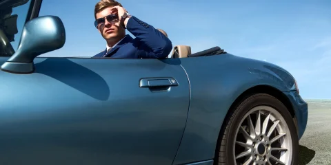 A person driving a stylish convertible car on a scenic road in Mexico