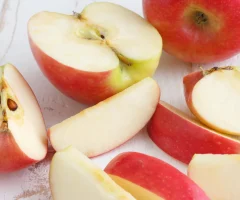 An apple cut into pieces on a wooden surface