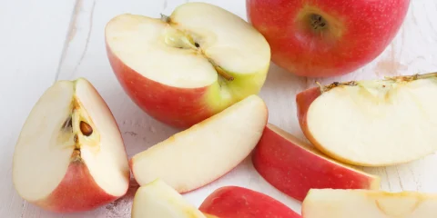 An apple cut into pieces on a wooden surface