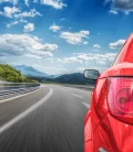 A vibrant red car driving along a scenic road in Mexico