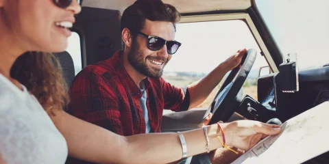 A couple sitting inside their car, looking at a map while planning their trip