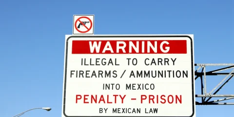 A warning sign displaying the message that it is illegal to cross arms into Mexico.