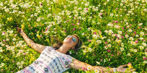 A woman lying peacefully in a field of grass, enjoying the outdoors