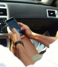 A man holding his cellphone for navigation while driving inside a car