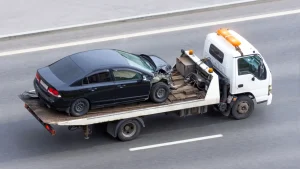 A car being towed on a flatbed tow truck along a road.