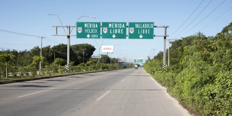 A road in Mexico with signs pointing to Mérida, Valladolid, and Holbox