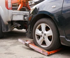 A close-up of a car's tire being lifted by a tow truck, showing the process of it being towed away.