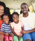 A family of four happily preparing for a road trip to Mexico