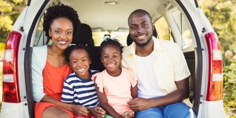 A family of four happily preparing for a road trip to Mexico