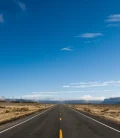 A lonely, empty road stretching into the horizon, surrounded by scenic landscapes.