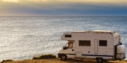 An RV parked in front of the sea, offering a stunning view of the ocean and a peaceful getaway.