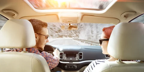 Two people inside their car having a conversation while on a road trip.