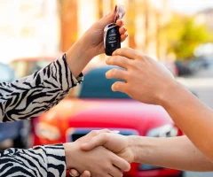 Dos personas cerrando un trato de un auto mientras una recibe las llaves