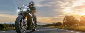 Un señor manejando su motocicleta por una carretera