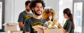 A person holding a cardboard box with a cheerful expression