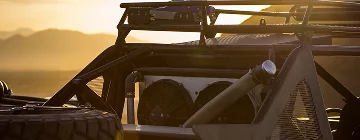 Close-up of an off-road race vehicle at sunset, with the sun shining through the metal frame. The webpage promotes Mexico insurance for off-road racers and rally enthusiasts, offering coverage for Baja and Sonora races.